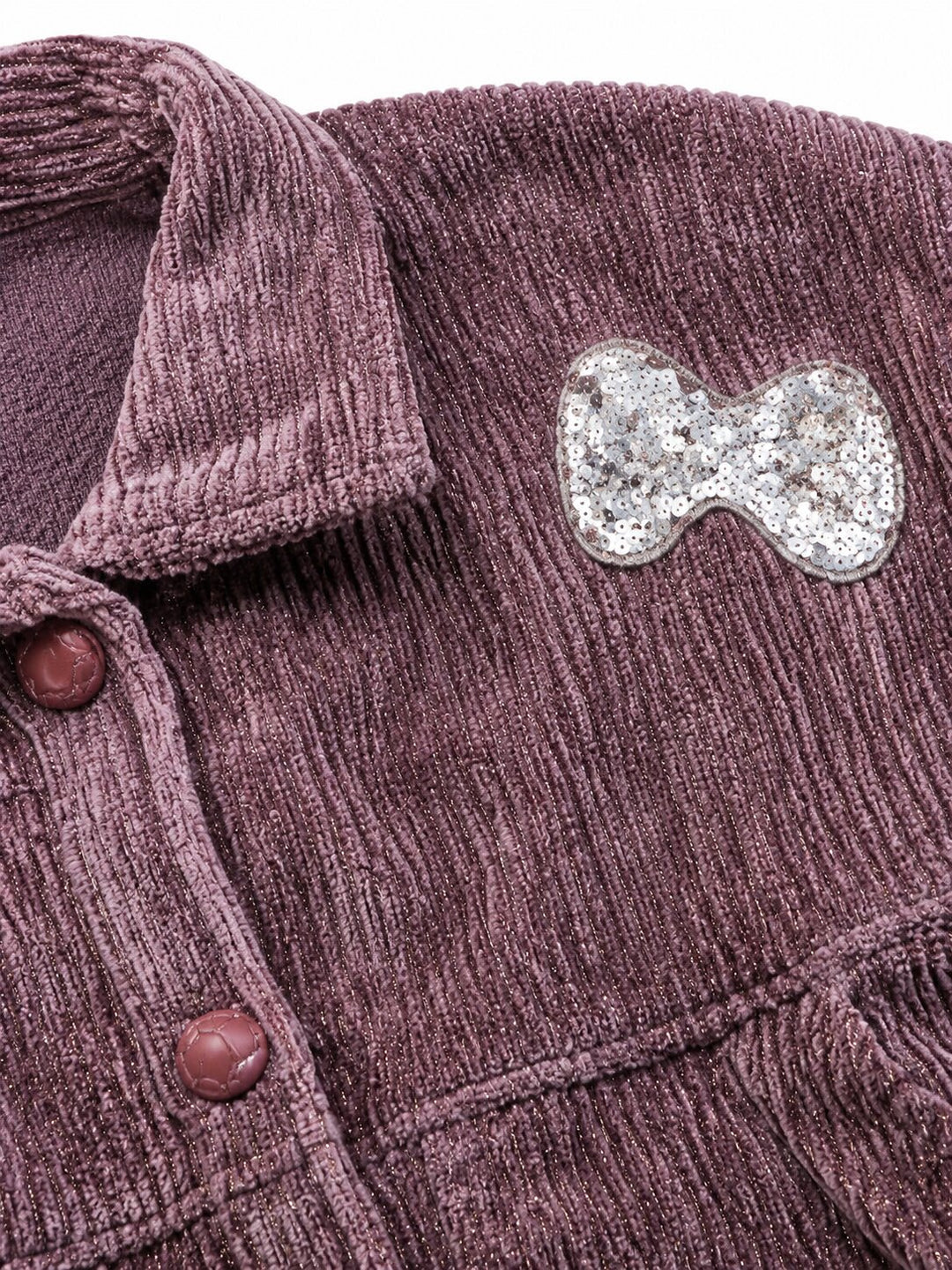 Close-up of a textured corduroy button-up shirt in a dusty mauve-purple color, featuring a silver glitter bow pin on the chest pocket.