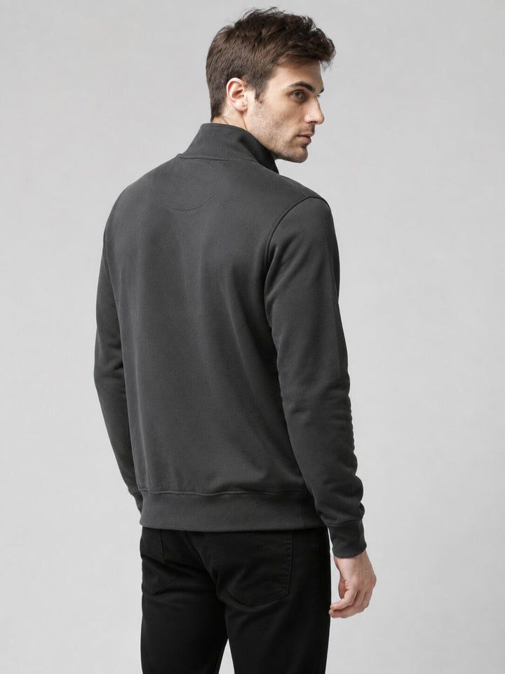 A man wearing a dark gray quarter-zip sweatshirt, shown from a rear three-quarter angle against a light gray studio background.