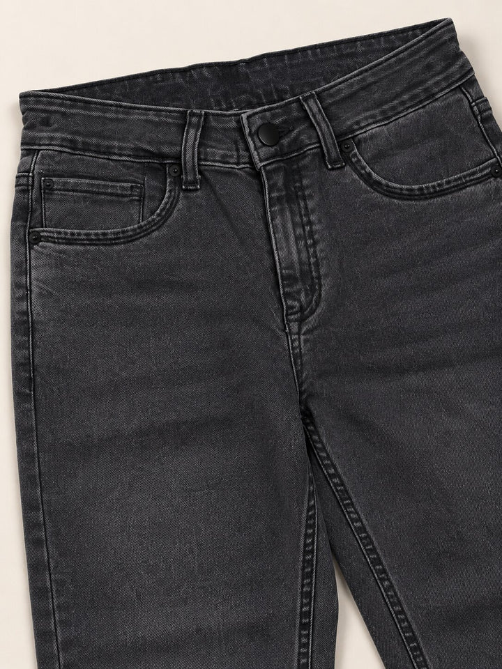 Close-up of dark gray washed denim jeans showing the front waistband, belt loops, button, and front pockets on a light neutral background.