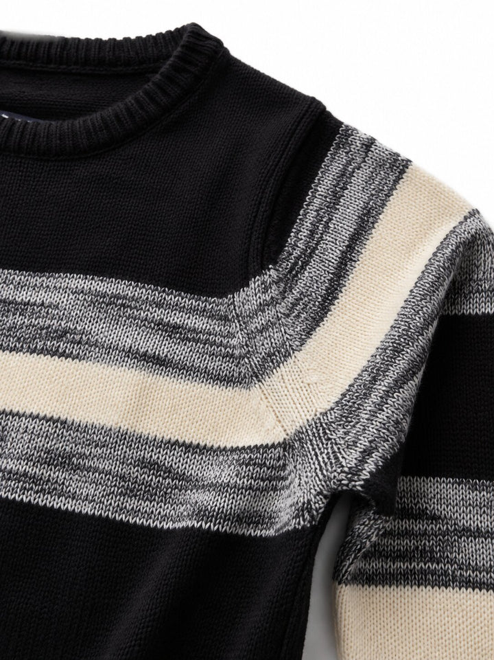 Close-up of a knit sweater with a black base and wide horizontal stripes in cream and heather gray.