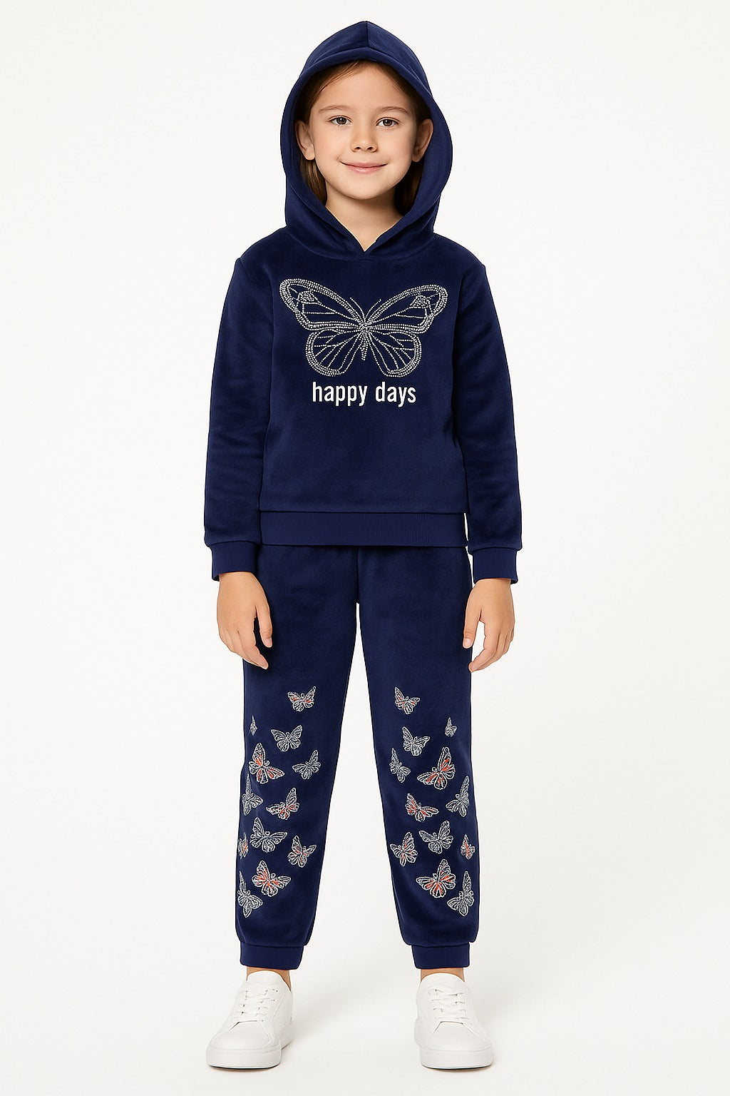 A young girl modeling a navy blue velour tracksuit with butterfly details. The set includes a hooded sweatshirt with a large white butterfly graphic and 'happy days' text on the chest, and matching jogger pants decorated with small butterfly prints.