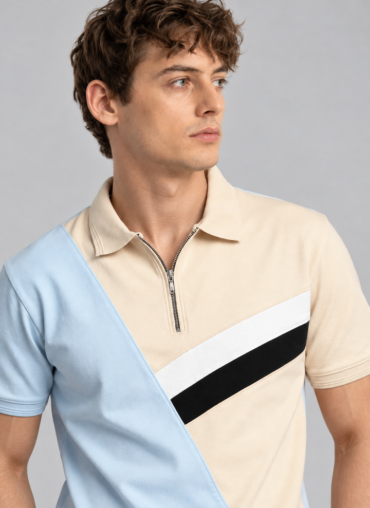 A man wearing a color-blocked short-sleeve polo shirt with a quarter-zip collar. The shirt features a light blue left side, a beige right side, a white diagonal stripe, and a black diagonal stripe across the chest.