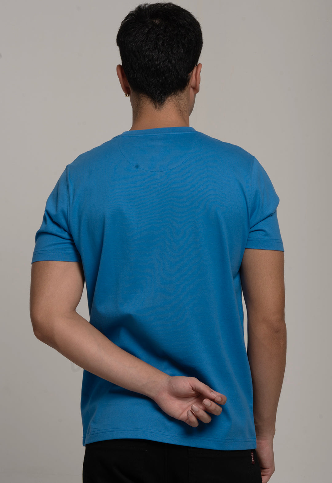 Person wearing a blue t-shirt against a gray background