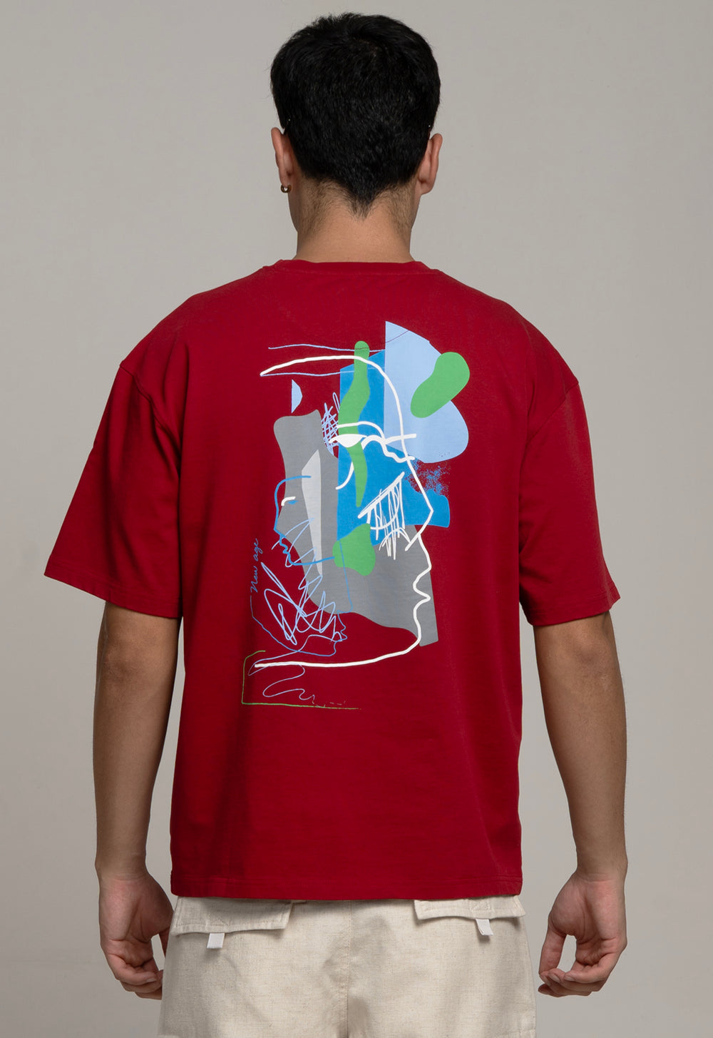 Person wearing a red t-shirt with a colorful graphic on the back against a plain background