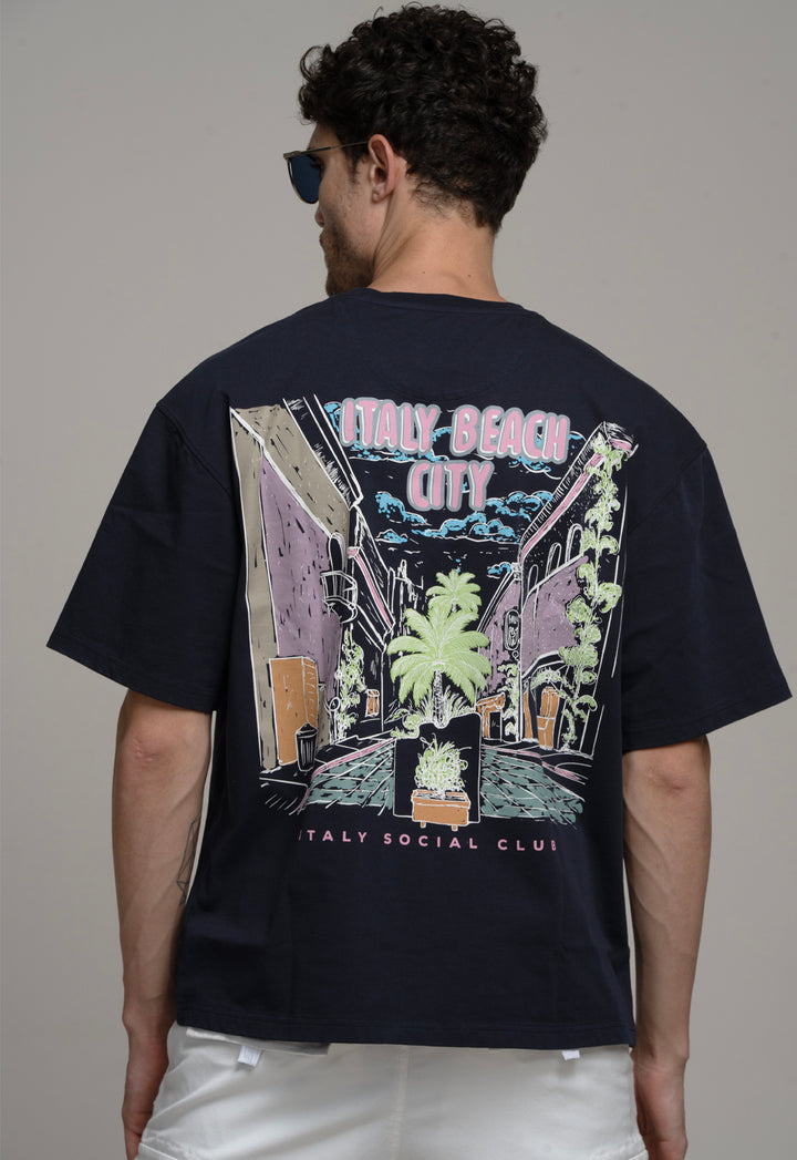 Person wearing a black t-shirt with a colorful graphic design on the back, standing against a plain background.