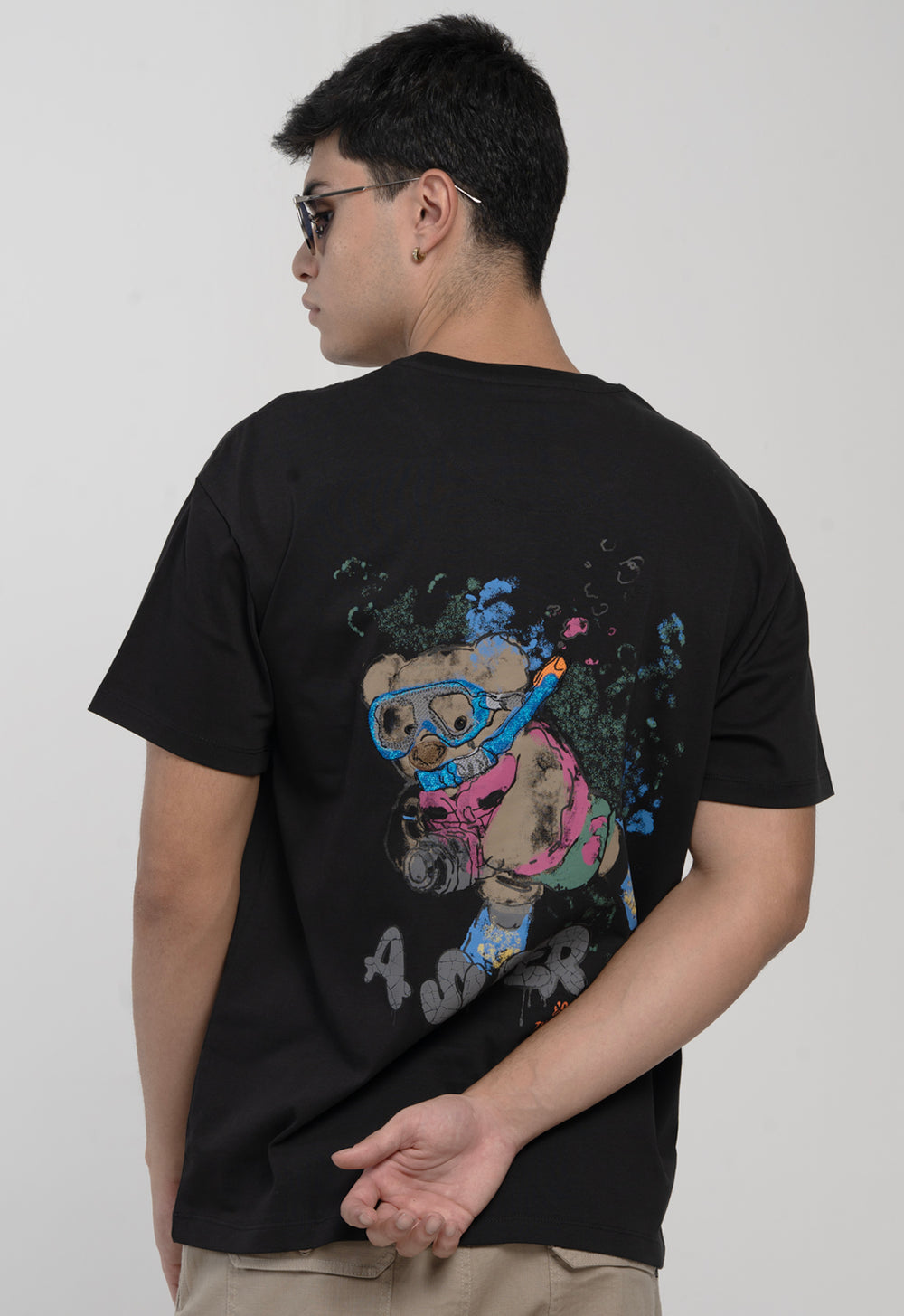 Person wearing a black t-shirt with colorful graphic design on the back against a plain background