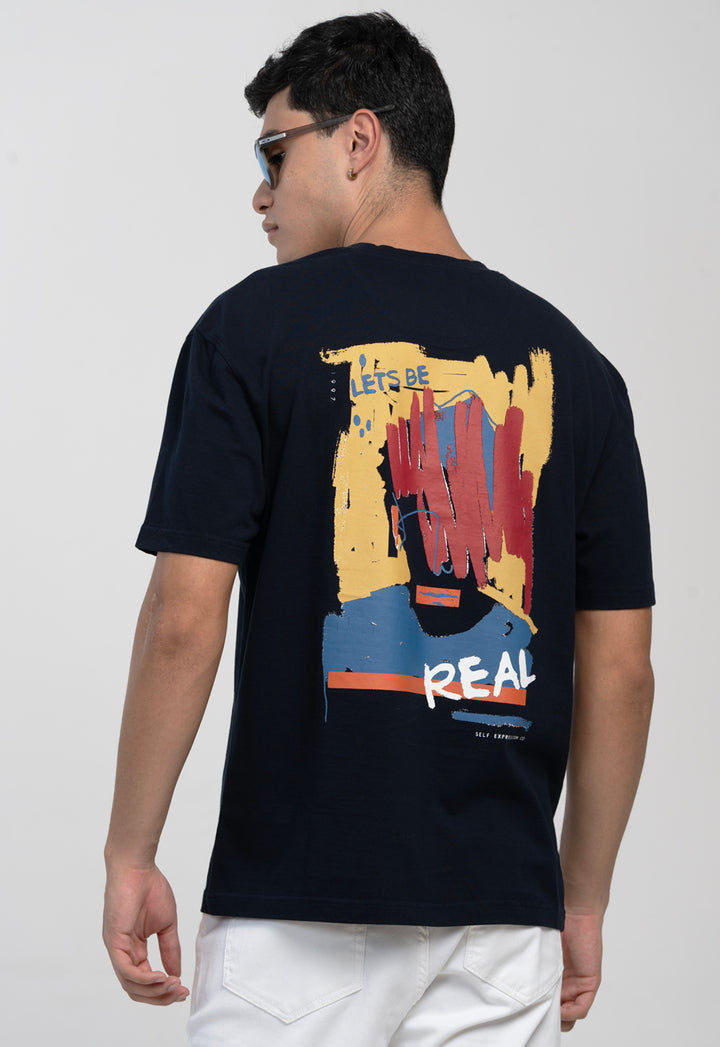 Person wearing a black t-shirt with colorful graphic and text on the back, standing against a plain background.