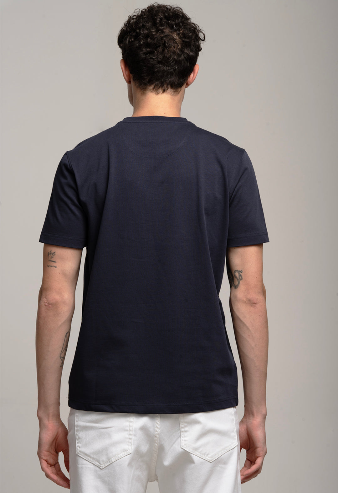 Person wearing a navy blue t-shirt and white pants on a gray background