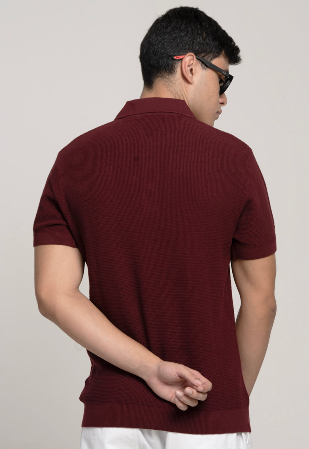 Man wearing a maroon polo shirt against a plain background