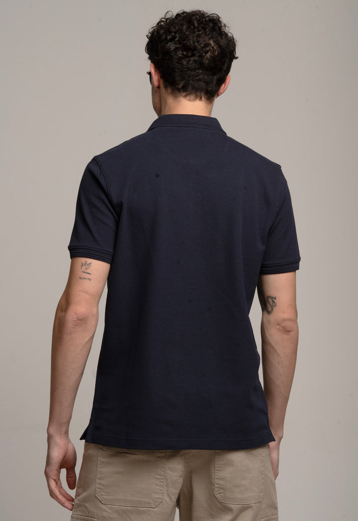Man wearing a navy blue polo shirt against a neutral background