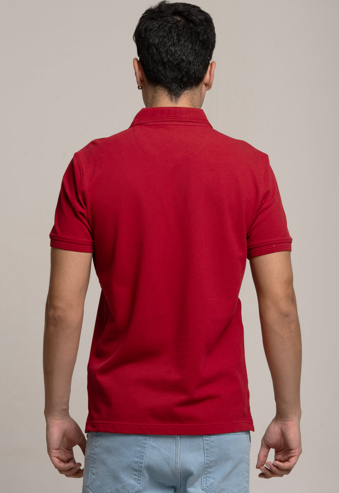 Man wearing a red polo shirt against a beige background