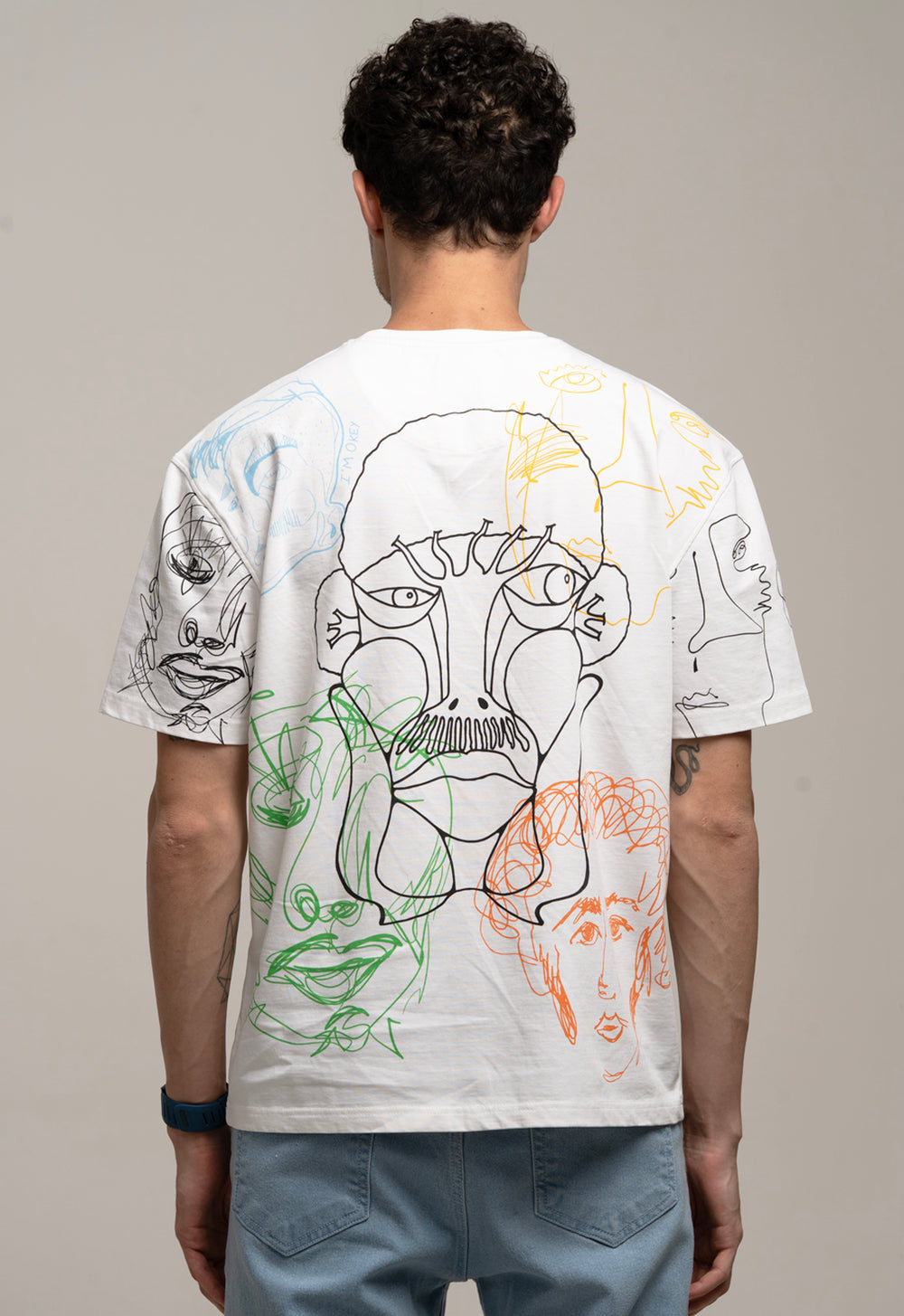Person wearing a white t-shirt with artistic designs on the back against a gray background