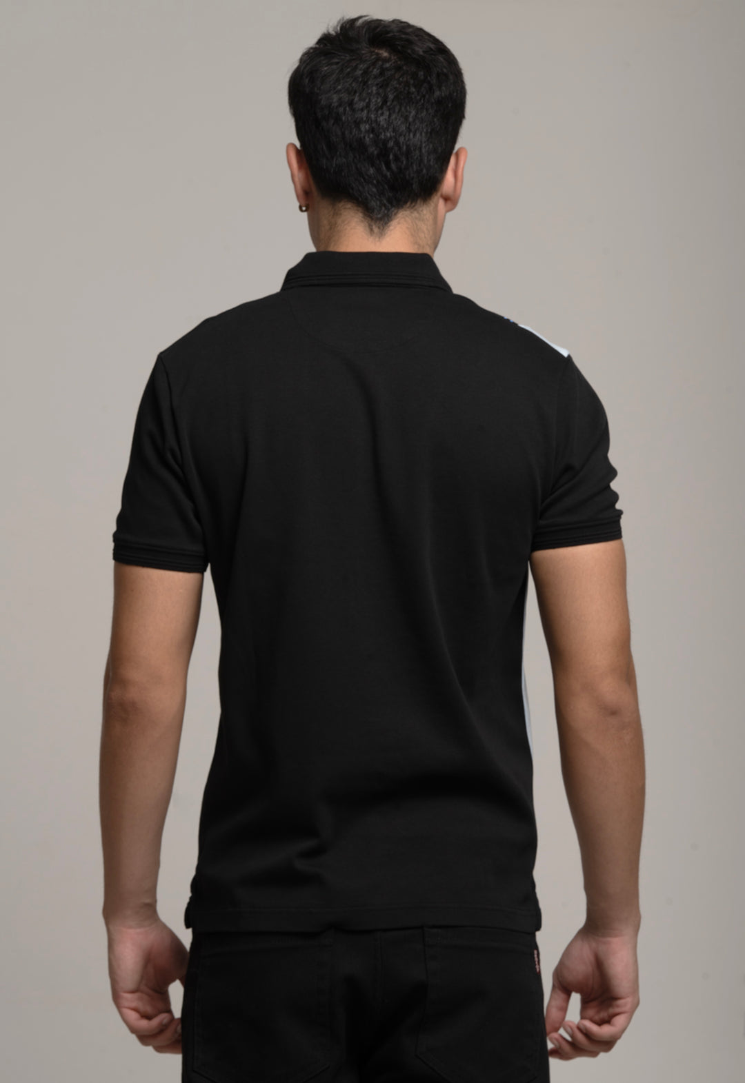 Man wearing a black polo shirt against a gray background