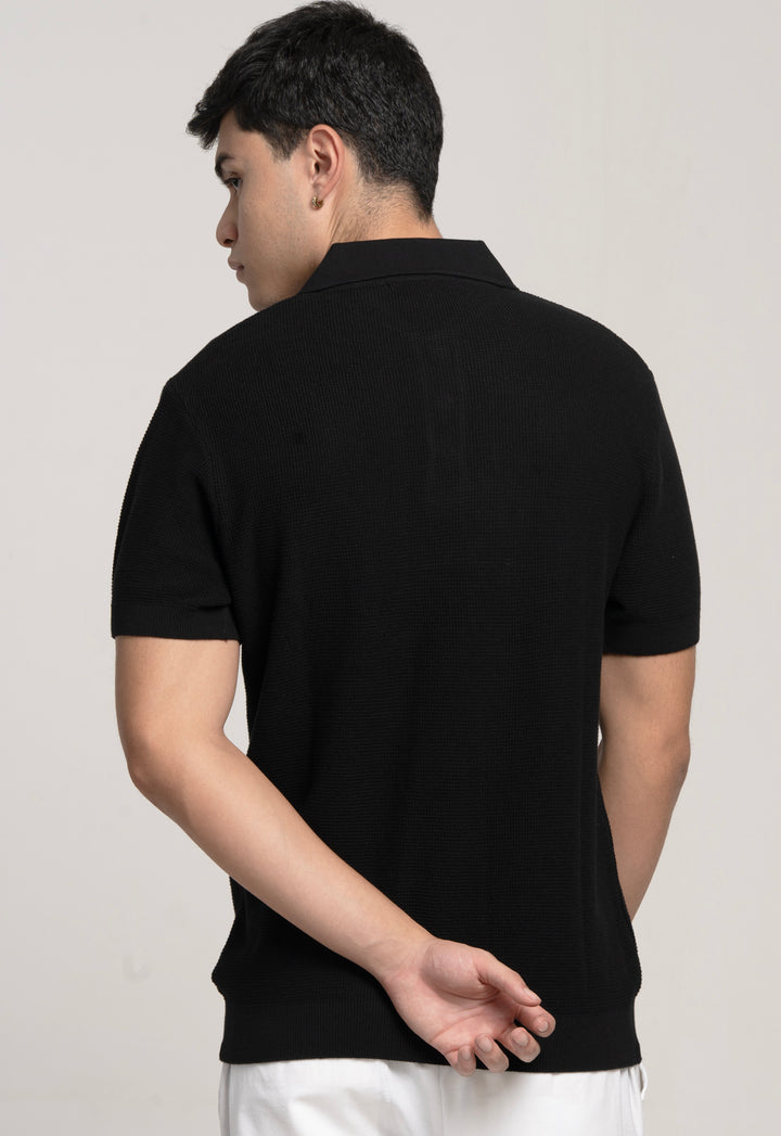 Person wearing a black polo shirt on a plain background