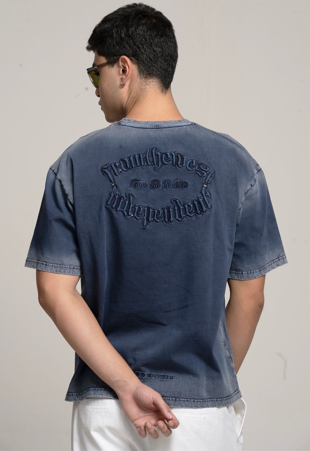 Person wearing a blue denim t-shirt with text on the back against a plain background