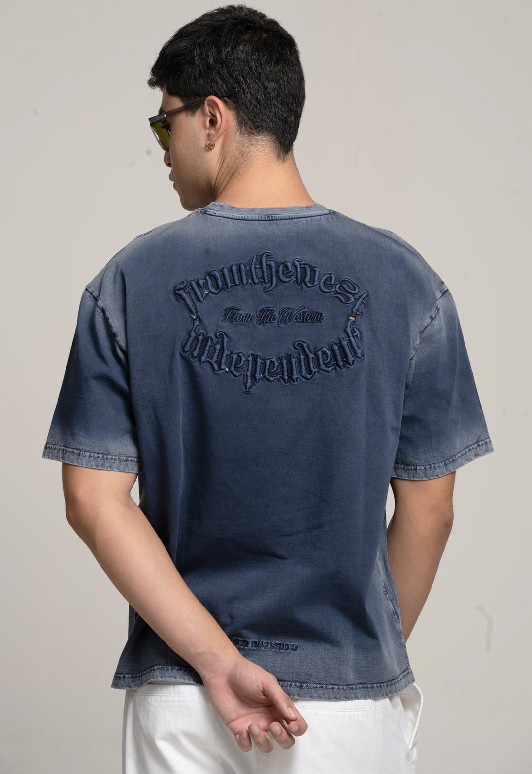 Person wearing a blue denim t-shirt with text on the back against a plain background