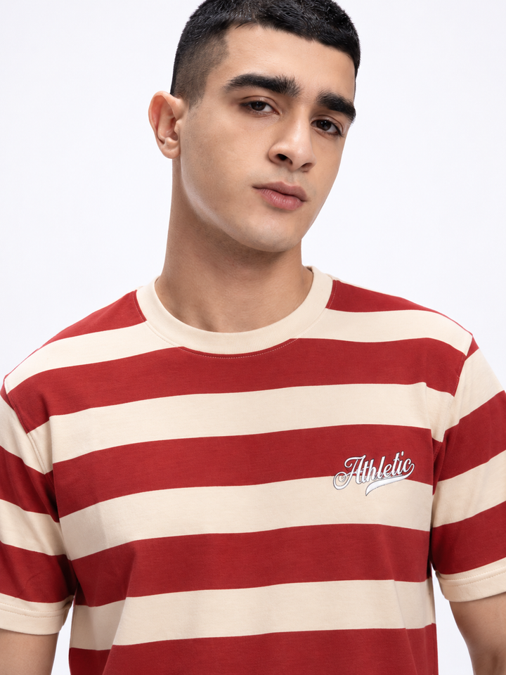 A man wearing a red and cream horizontal striped t-shirt with a white 'Athletic' script logo on the left chest, photographed against a clean white background.