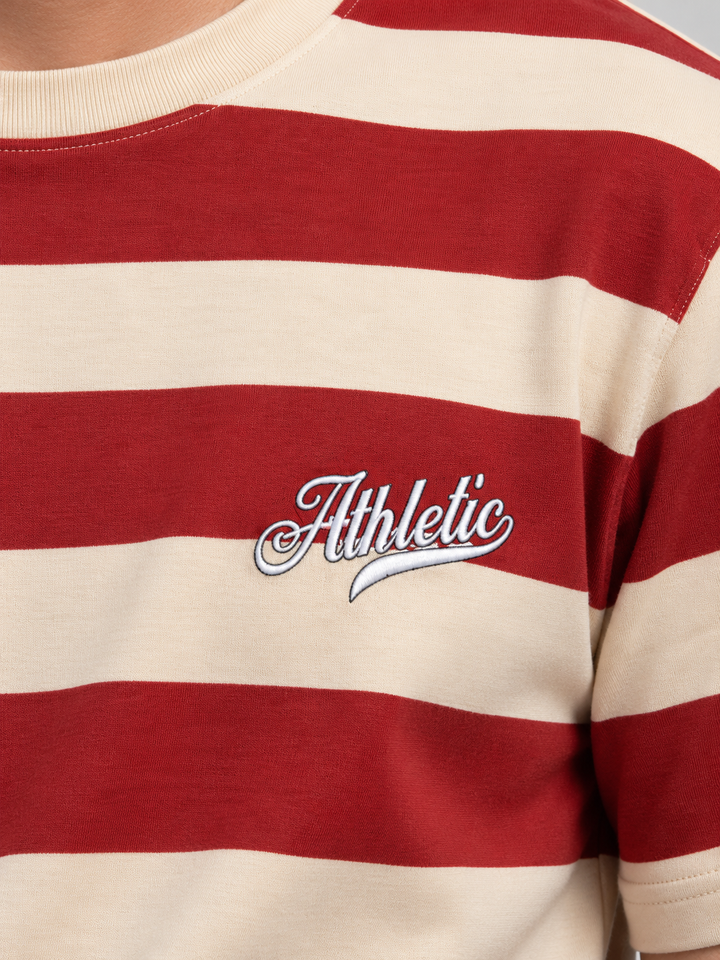 A close-up of a red and cream striped t-shirt featuring a white embroidered 'Athletic' script logo on the chest.