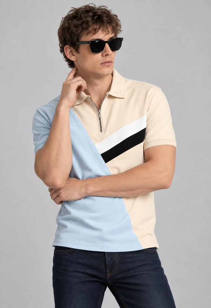 A man wearing a short-sleeve color-block polo shirt with a quarter-zip collar, dark sunglasses, and dark blue jeans, posed against a solid gray studio background.