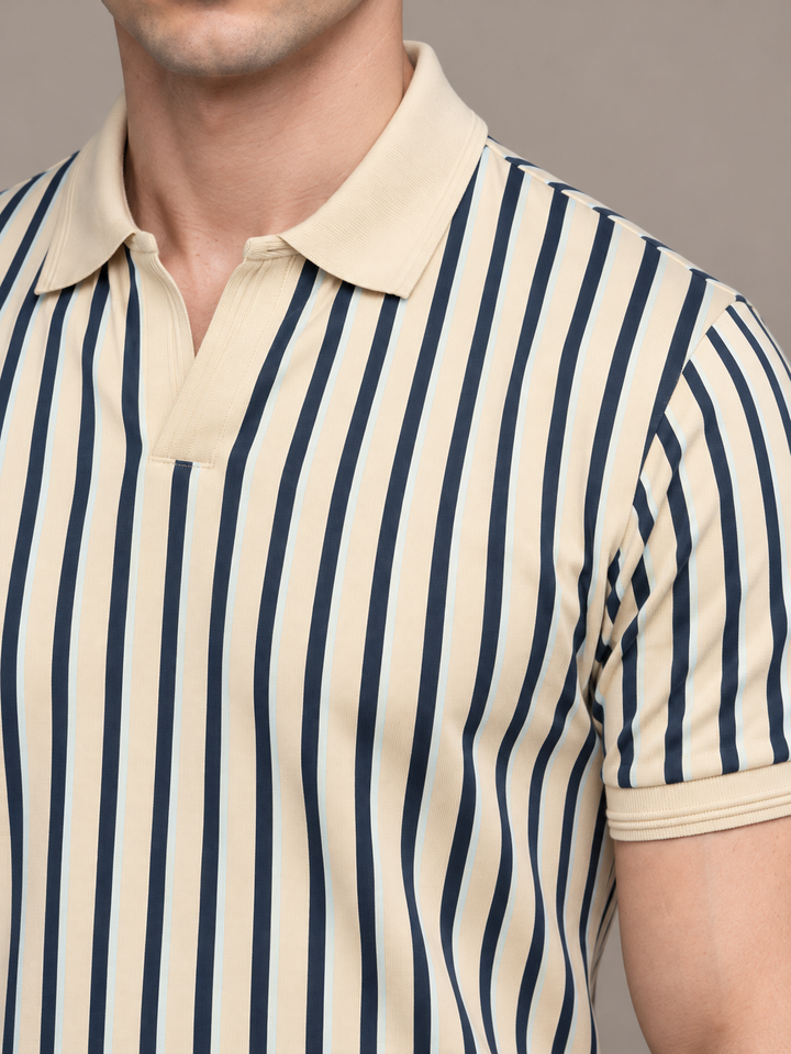 Close-up of a man wearing a short-sleeve polo shirt with vertical navy blue and cream stripes, featuring a solid cream collar and placket.