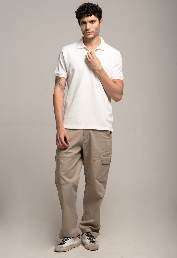 Man wearing a white polo shirt and beige pants against a gray background