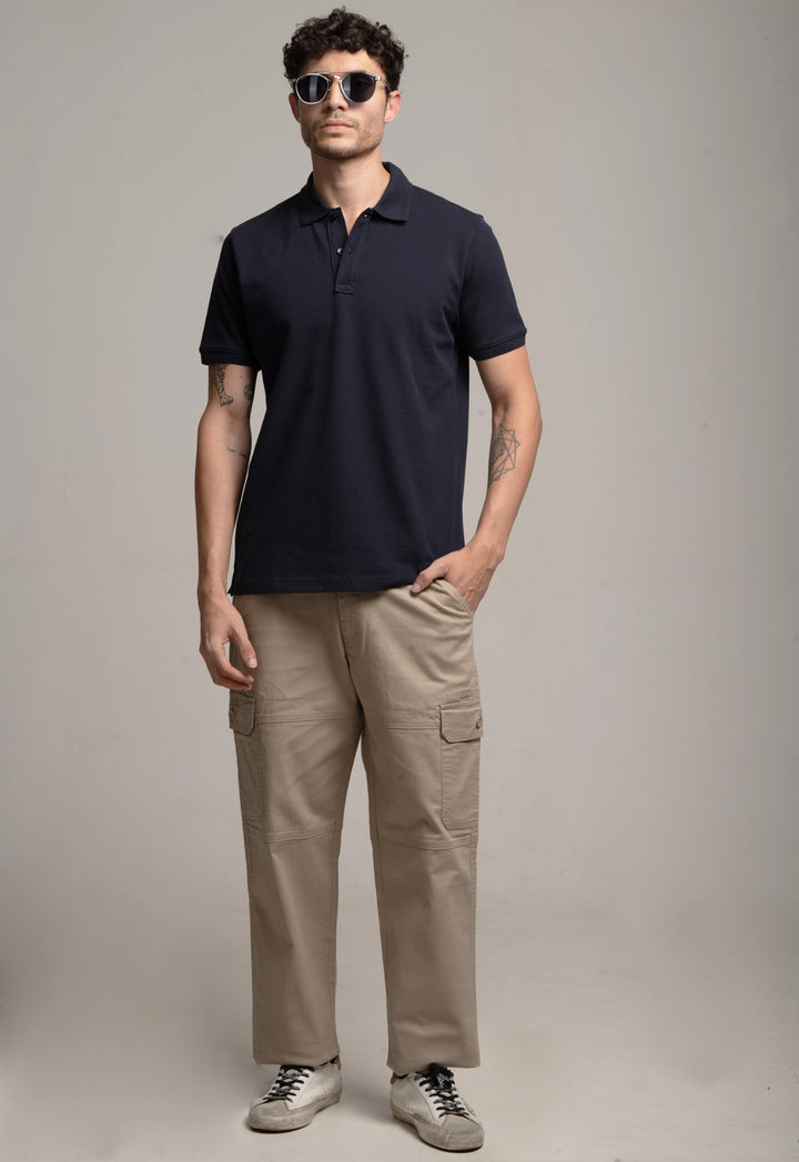 Man wearing a navy polo shirt and beige cargo pants against a plain background