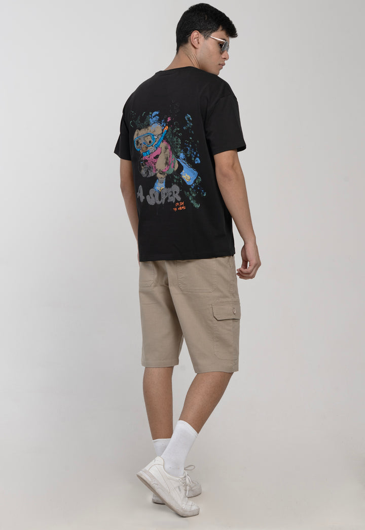 Person wearing a black t-shirt with a graphic design and beige shorts on a light gray background
