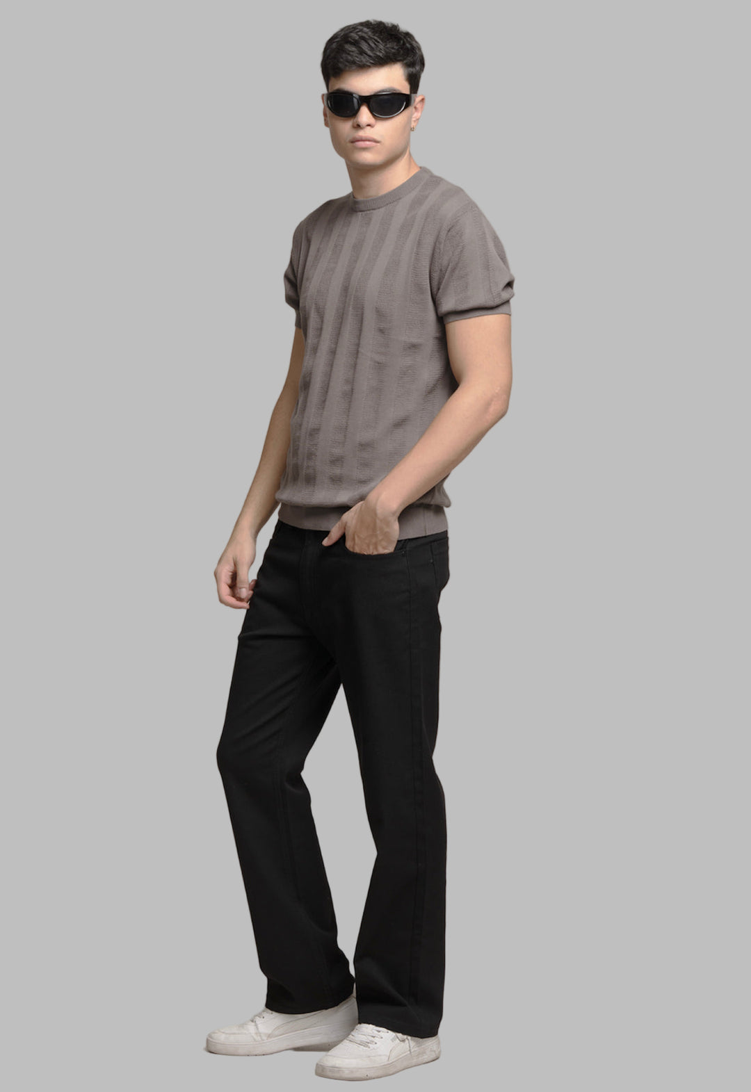 Man wearing a gray t-shirt, black pants, and sunglasses on a plain background
