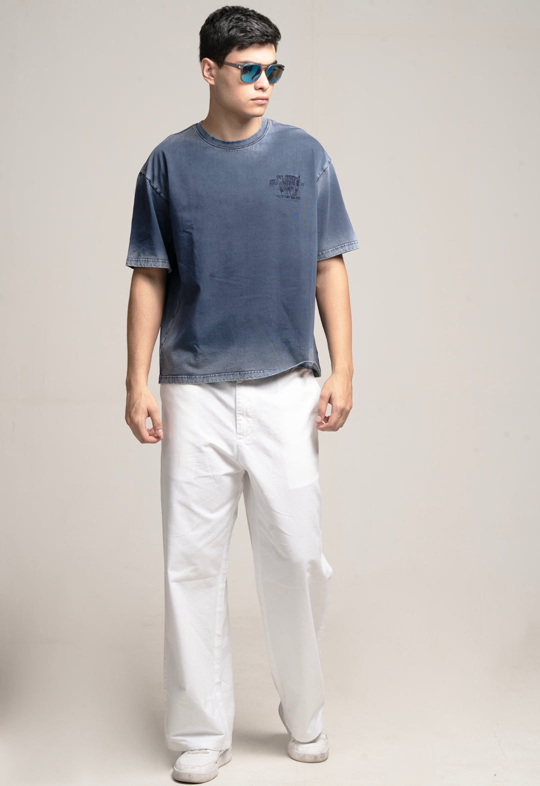 Person wearing a blue t-shirt and white pants on a plain background