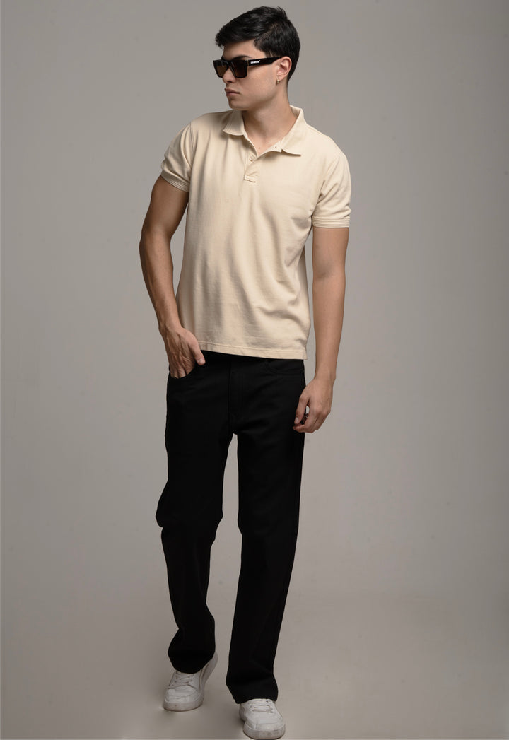 Man wearing a beige polo shirt and black pants against a gray background