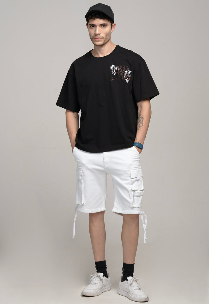 Man wearing a black t-shirt with a graphic design and white cargo shorts on a gray background