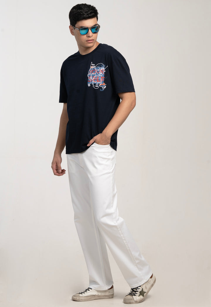 Man wearing a black t-shirt with a graphic design and white pants on a light gray background