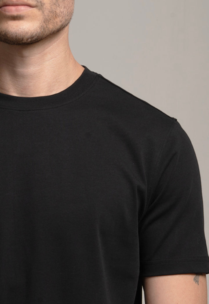Close-up of a person wearing a black t-shirt against a neutral background