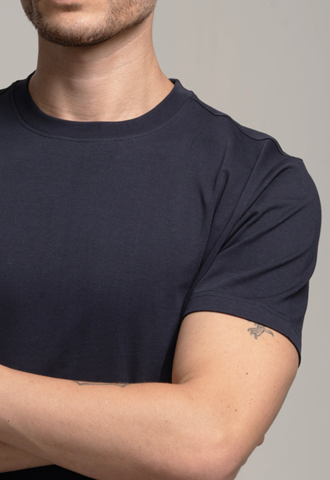 Person wearing a dark blue t-shirt against a neutral background