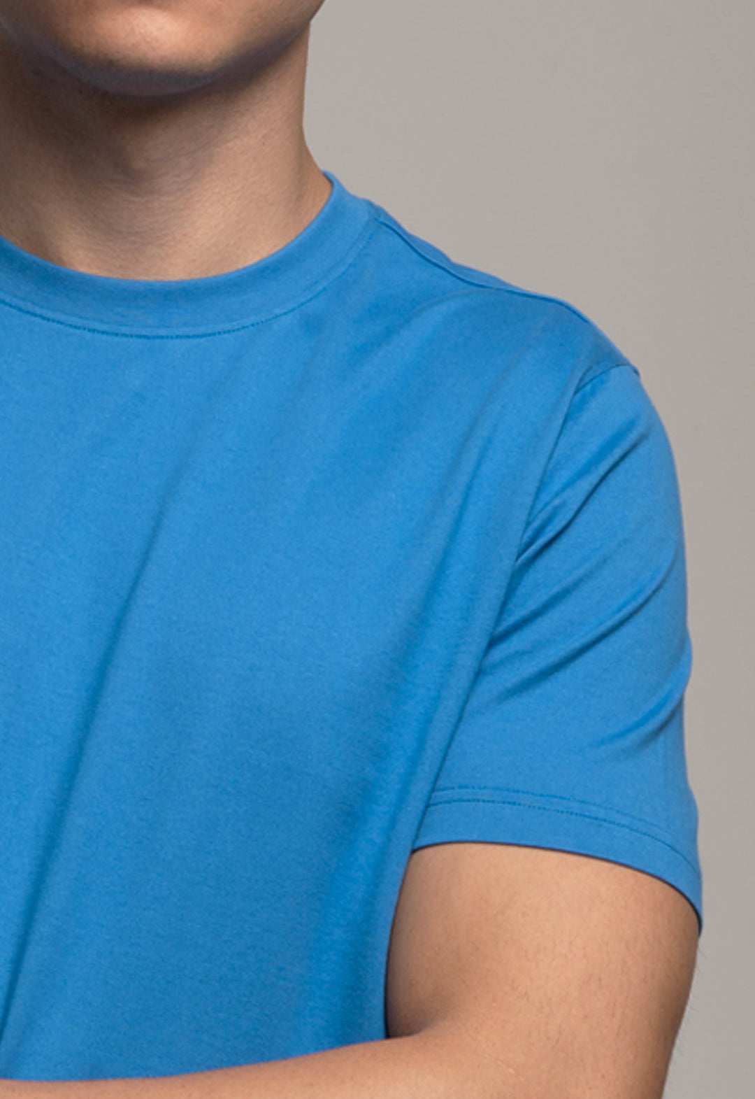 Blue t-shirt worn by a person on a gray background