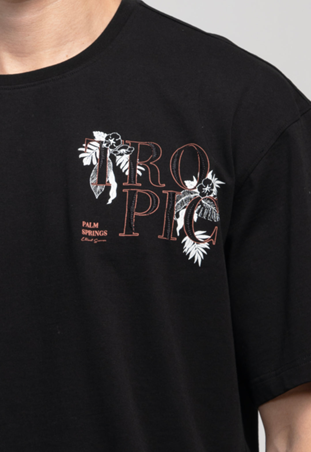 Black t-shirt with 'Tropico' design featuring palm trees and flowers on a plain background
