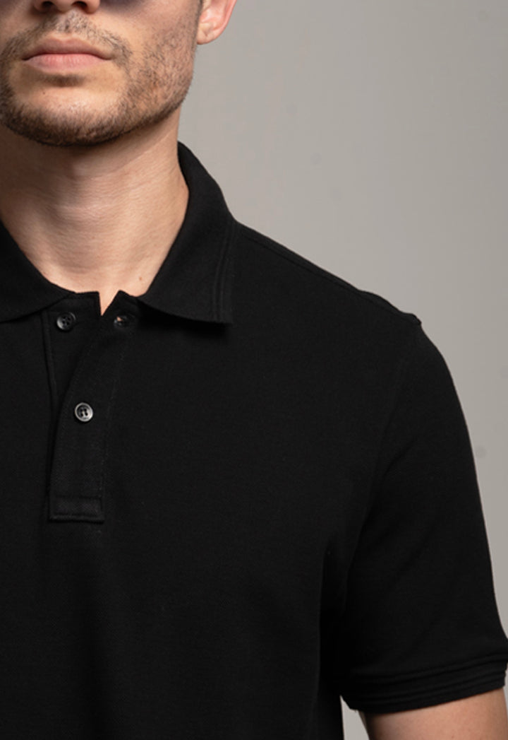 Man wearing a black polo shirt against a gray background