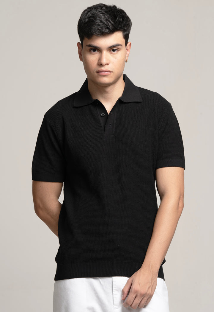 Man wearing a black polo shirt against a plain background