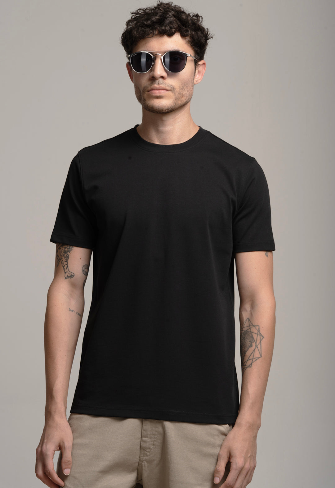 Man wearing a black t-shirt and sunglasses against a gray background