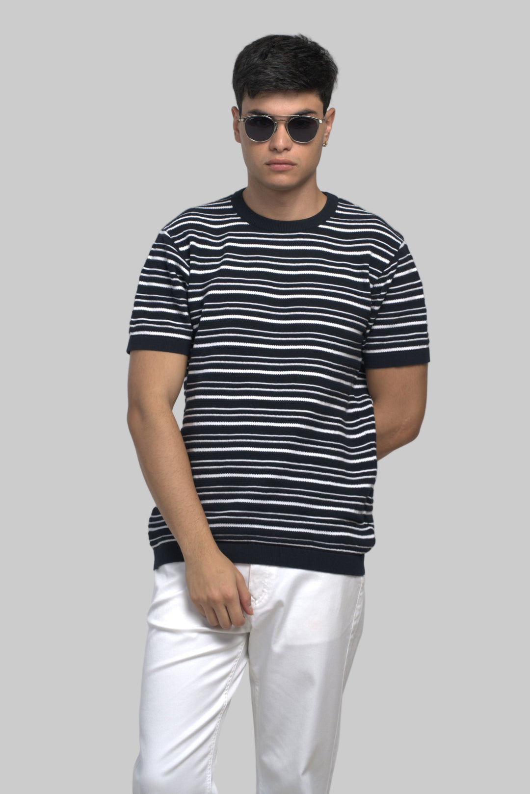 Man wearing a black and white striped shirt with sunglasses on a plain background