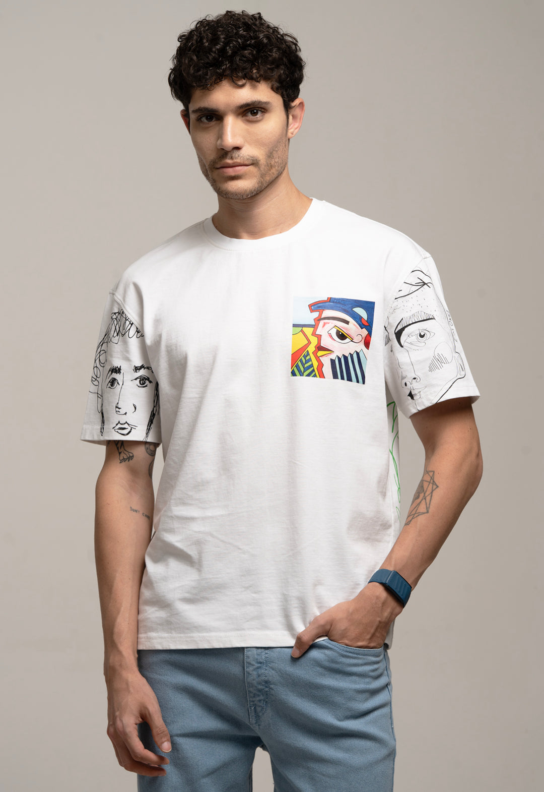 Man wearing a white t-shirt with artistic designs on a plain background