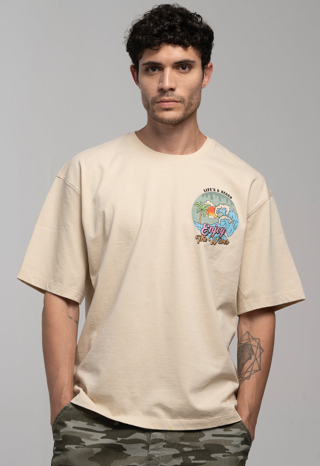 Man wearing a beige t-shirt with a colorful graphic design on a gray background