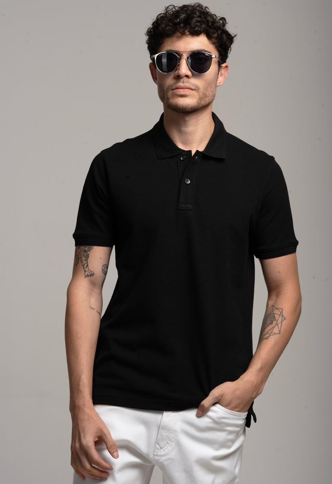 Man wearing a black polo shirt and sunglasses against a gray background