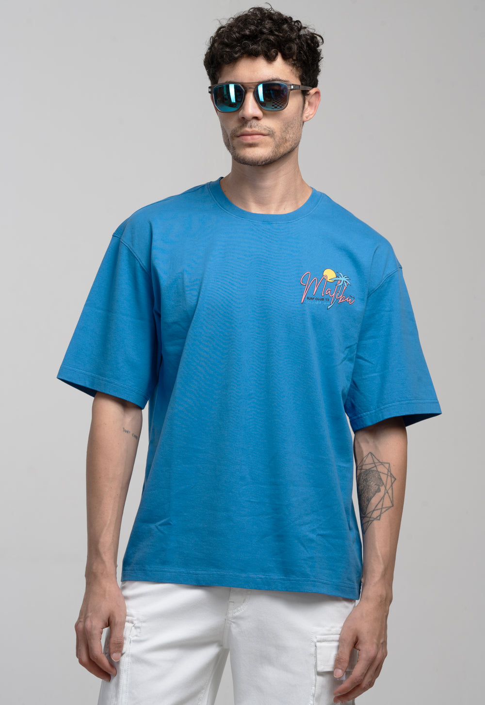 Man wearing a blue t-shirt with a logo on a gray background