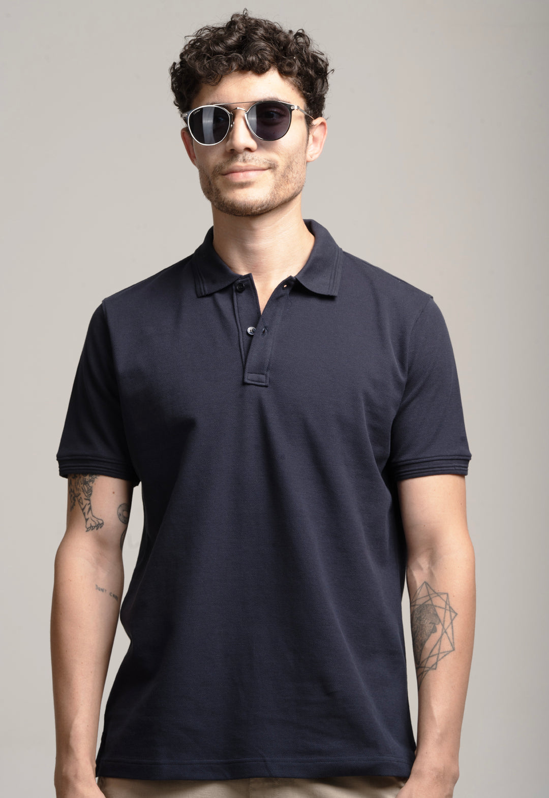 Man wearing a navy blue polo shirt against a gray background