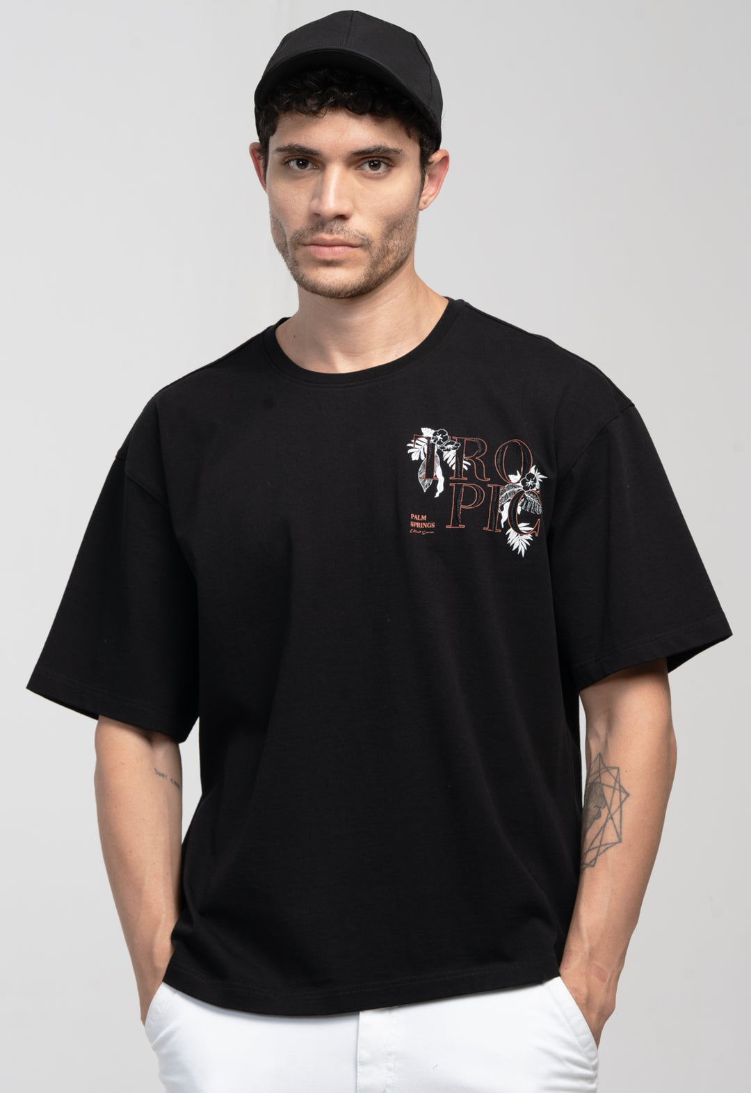 Man wearing a black t-shirt with a graphic design on a plain background