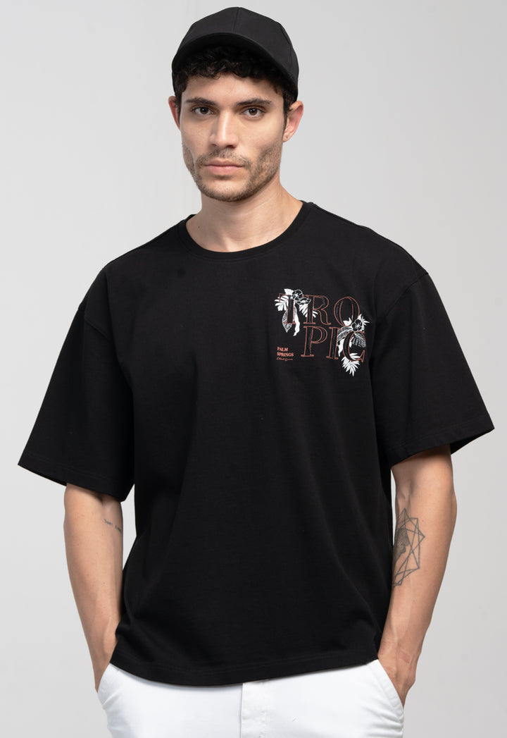 Man wearing a black t-shirt with a graphic design on a plain background