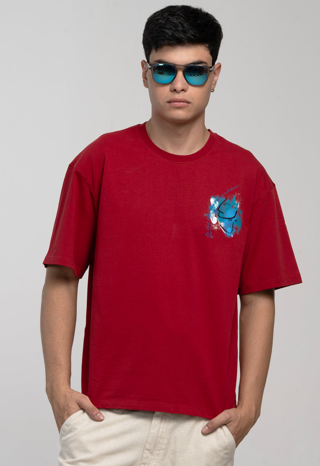 Person wearing a red t-shirt with a blue graphic design on a plain background