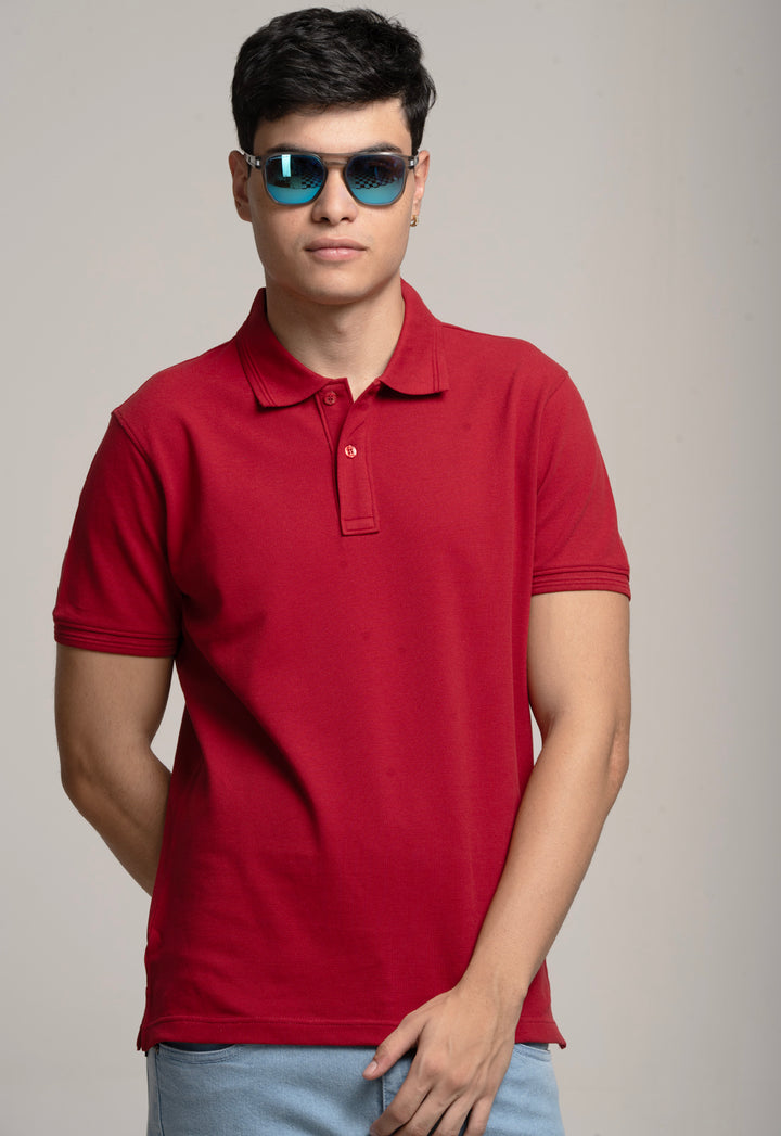 Man wearing a red polo shirt and sunglasses against a plain background