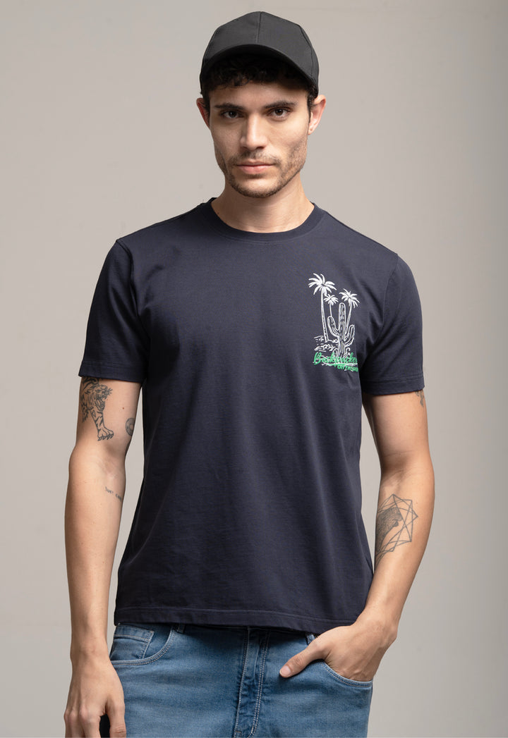 Man wearing a navy t-shirt with a palm tree design on a gray background